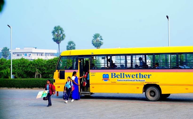A teacher welcoming a child from the Bellwether school bus