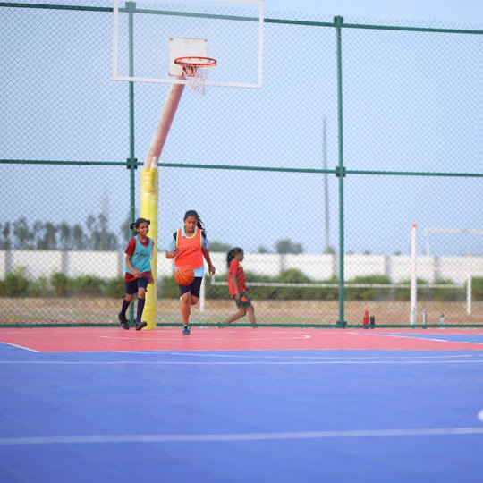 Bellwether students playing beneath the basketball hoop on the school court