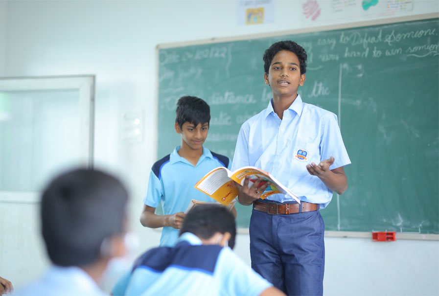 A Bellwether student standing and reading aloud to classmates