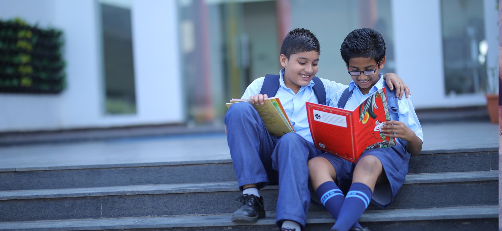 Two Bellwether students reading a book together on the school steps